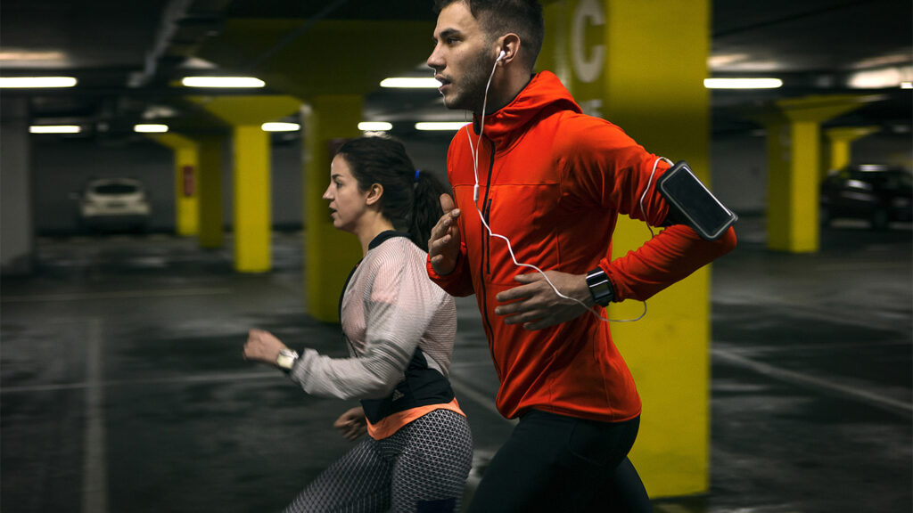 Man and woman running in a carpark together